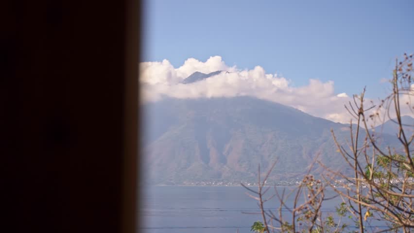 Viewing the Lake Aititlan volcano from an apartment window, through the tress in Guatemala, Slow motion