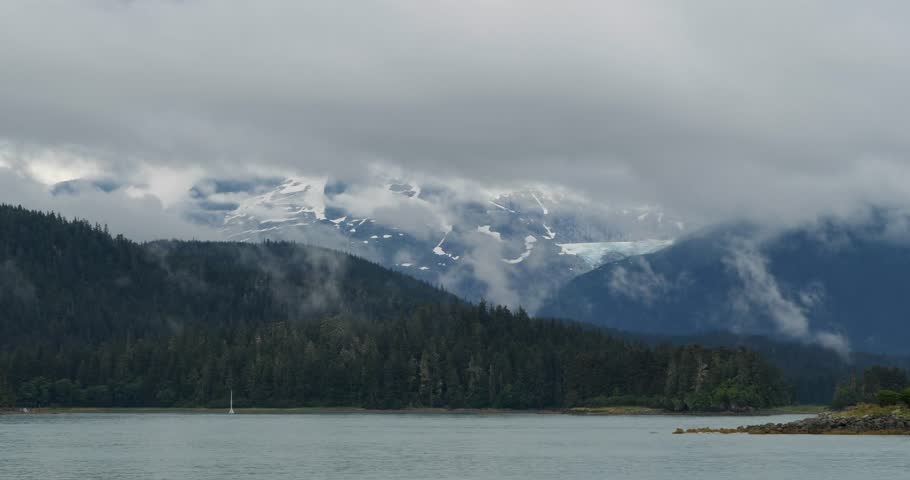 Snow capped mountains covered with cloud in Juneau, Alaska. Suspended glacier in the background.