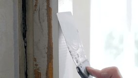 Closeup slow motion video of hand holding spatula and removing old paint from wooden door