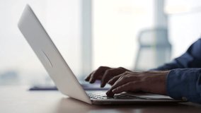 Side view. Silhouette. Close up of male hands typing on a laptop keyboard. Businessman or IT programmer uses a computer while sitting at a desk at a workplace in a business office. Man fingers texting - Powered by Shutterstock - Get 15% off with code: PIKWIZARD15