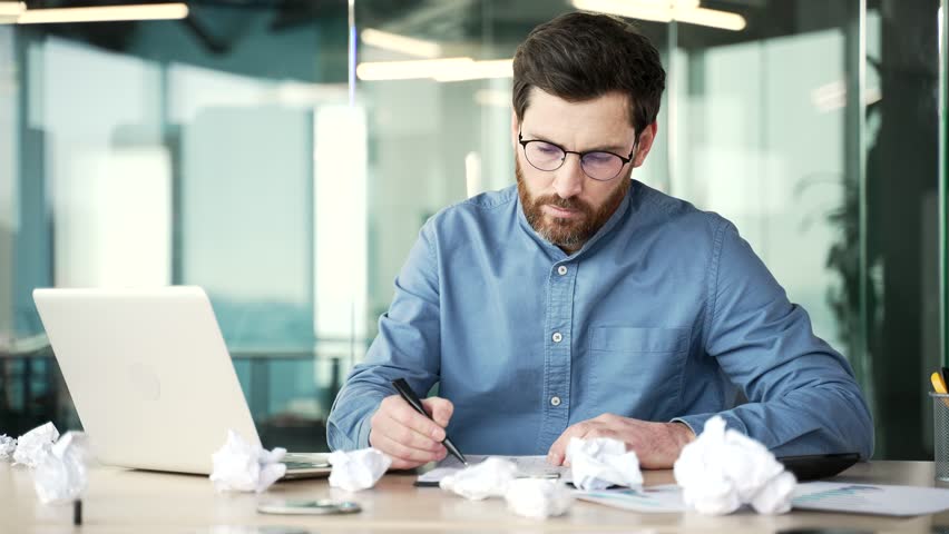 Overworked bearded financier in glasses is bored filling out documents sitting at workplace in business office. Exhausted accountant is tired of doing paper work. Man has depression, despair. Crisis Royalty-Free Stock Footage #3434701603