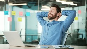 Happy handsome bearded businessman finished work on laptop while sitting at workplace in business office. Smiling satisfied male employee puts his hands behind his head, stretches in chair. Work done - Powered by Shutterstock - Get 15% off with code: PIKWIZARD15