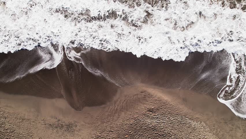 Ocean waves crashing on deserted sandy beach, Plage de Grande Anse bay, Guadeloupe, French Antilles. Aerial sideways directly above and space for copy