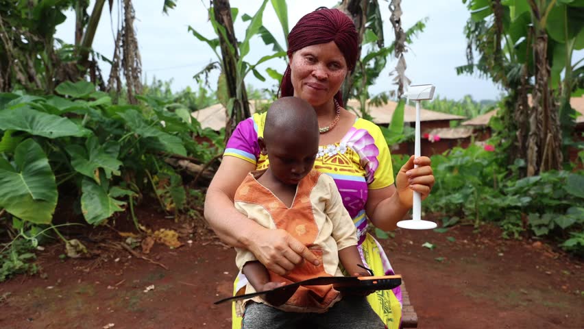 An African mother explains to her son how to live in a sustainable world with a wind turbine and photovoltaic panels