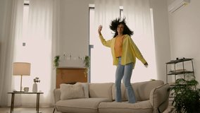 Active funny crazy African American girl young happy woman jumping on sofa couch in living room excited female jump dance loud music home party rejoicing carefree joyful lady weekend vacation freedom - Powered by Shutterstock - Get 15% off with code: PIKWIZARD15