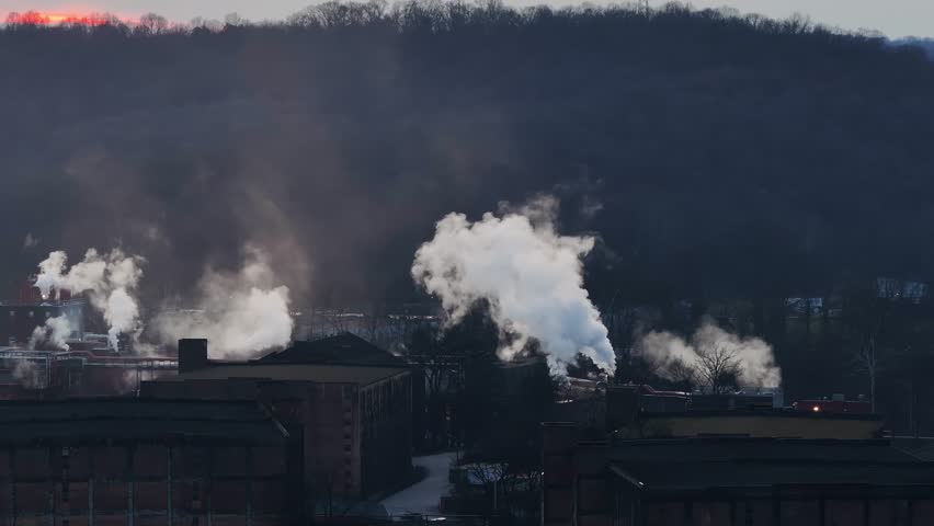 bourbon distillery in Frankfort kentucky with large clouds of smoke over the wooden rick houses during sunset on the bourbon trail AERIAL STATIC