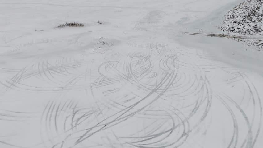 Drone captures intricate car tracks left by drifting cars on the icy surface. Winter transforms a flooded field into ice Royalty-Free Stock Footage #3434794065