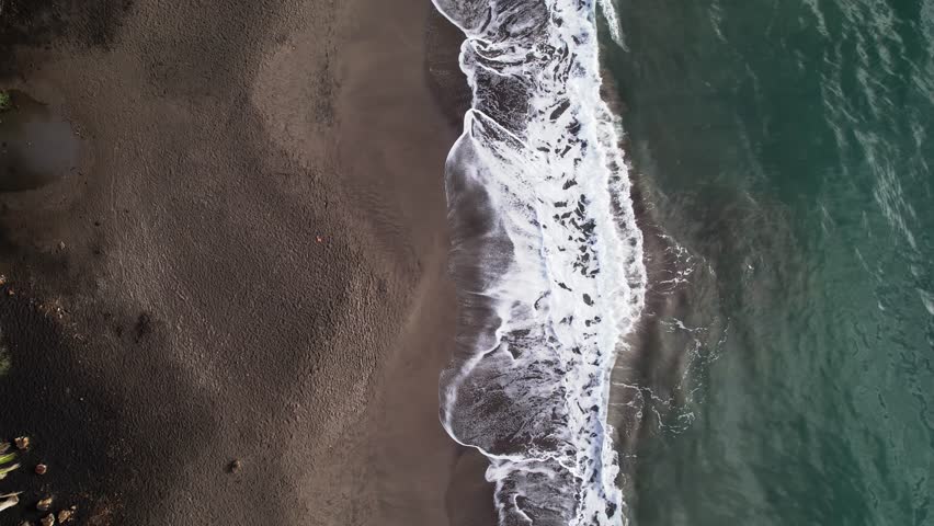 Waves breaking on sandy beach, Plage de Grande Anse bay, Trois Rivieres in Guadeloupe. Aerial top-down view