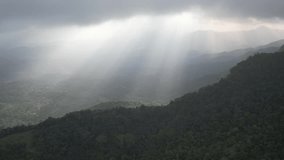 Aerial view of a green rain cloud cover tropical rain forest mountain during the sun rise with rays in the hill county Sri Lanka