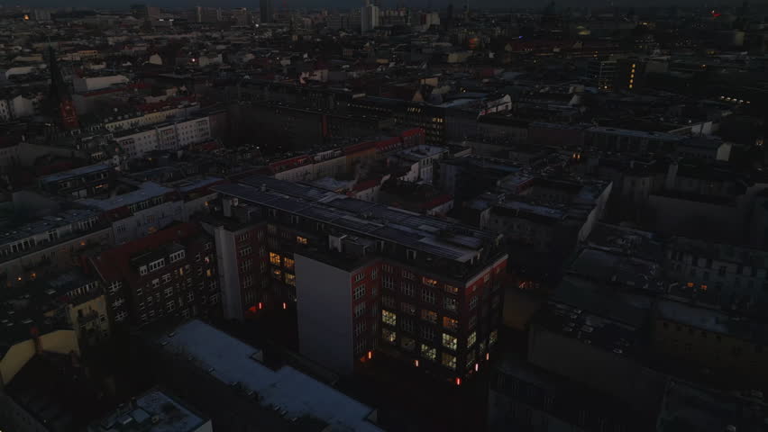 High angle view of apartment buildings in urban borough at dusk. Tilt up reveal evening cityscape with tall TV tower. Berlin, Germany