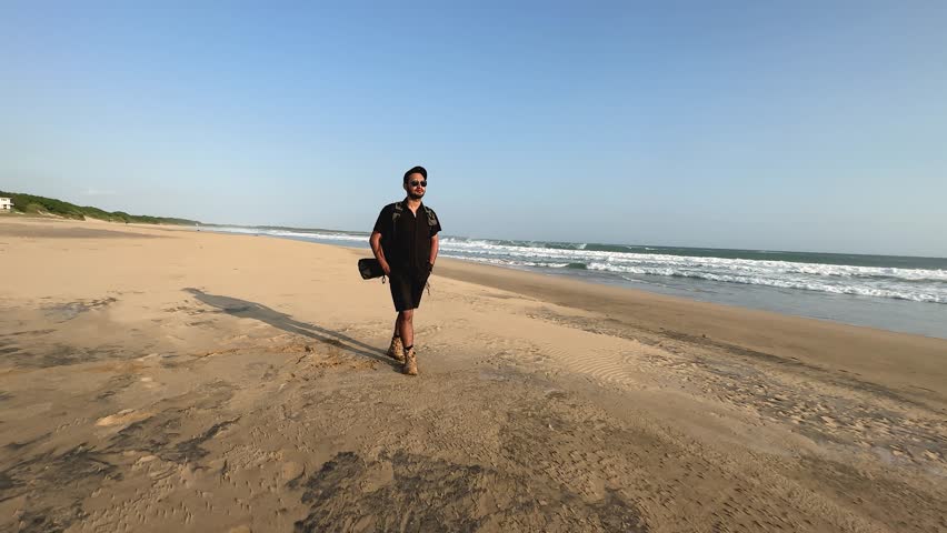 A handsome young man is walking on the beach