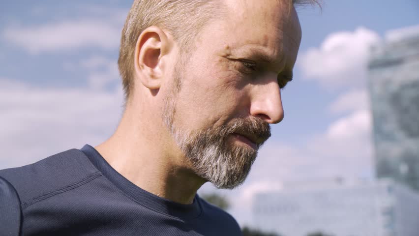 A handsome middle-aged Caucasian man looks seriously at the camera - face closeup - blue sky in the background