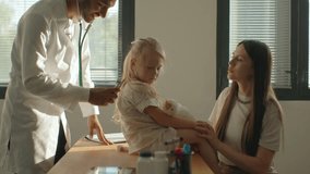 A preschool-aged girl with her mother is being examined by a pediatrician. A young man, a pulmonologist, conducts an examination using a phalendoscope. - Powered by Shutterstock - Get 15% off with code: PIKWIZARD15