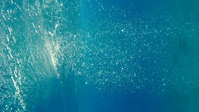 Vertical video, Slow motion of air bubbles floating from sea bottom to the water surface with waves. Air bubbles in the blue water