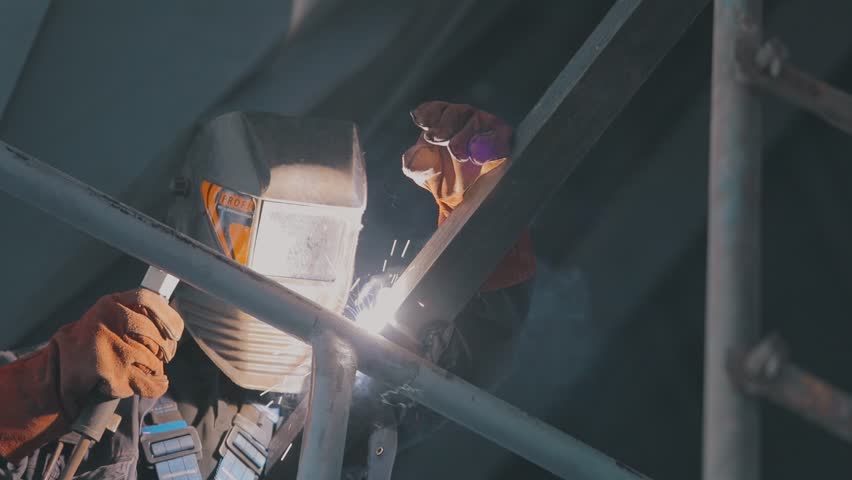 A welder welds metal parts. A welder in a factory. Construction worker Royalty-Free Stock Footage #3435057477