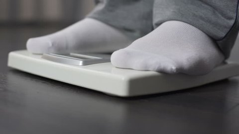 Obese man measuring his weight on health scale, dieting and weightloss, close-up