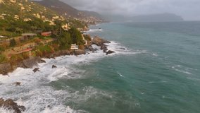 Nervi in genoa, italy with waves crashing on rocky shore, houses nestled on hillside, aerial view