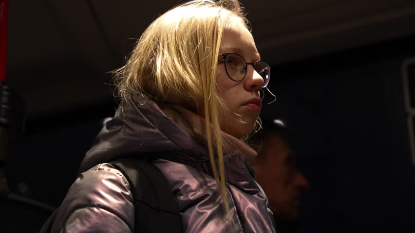 Young beautiful girl sites in the bus early winter morning to go to school. Sleepy, tired sad, depressed girl portrait.