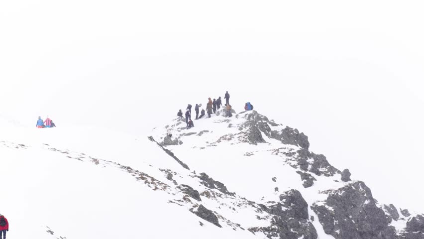 Distant view, a group of people on a snowy mountain peak during a heavy snowfall
