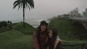 Couple walking by the ocean, filming themselves on go pro.Loving couple walking on foggy weather, couple taking selfie.
