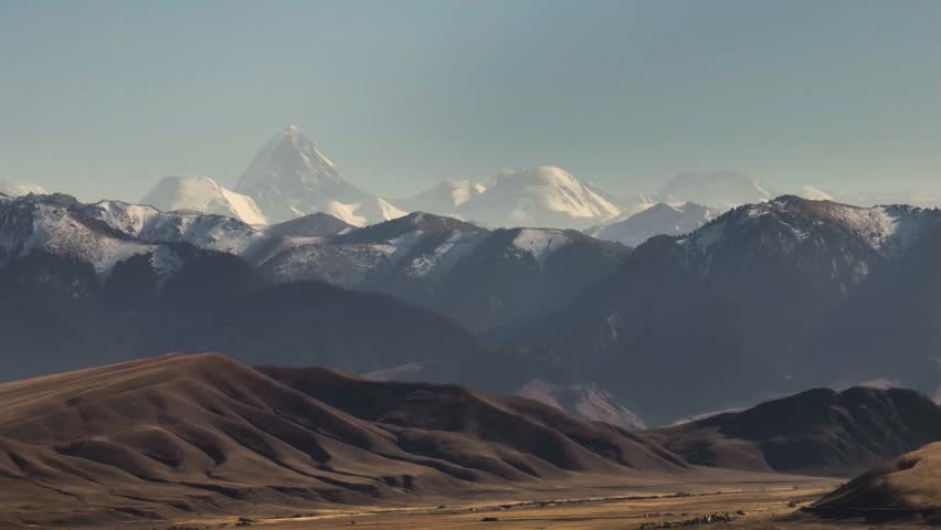 Mountainous terrain with beautiful skin rocky slopes with snow peaks background. Martian plateau landscape in Kazakhstan at summer sunny sunset.