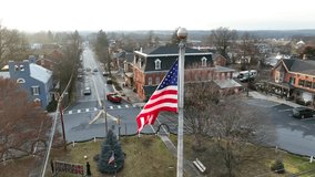 Waving american flag in center of roundabout in small american community. Sunset during Christmas time. Aerial close up orbit shot. - Powered by Shutterstock - Get 15% off with code: PIKWIZARD15