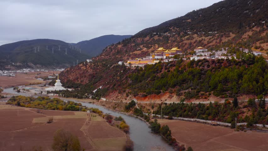 Golden religious temple stop of pilgrimage overlooks beautiful river in Autumn, Yading Valley village