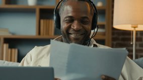 African American man businessman freelancer checking paperwork at home smiling male entrepreneur reading documents analyzing financial papers enter data into laptop listening on headphones video call - Powered by Shutterstock - Get 15% off with code: PIKWIZARD15