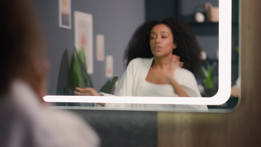 African American funny active happy woman looking at mirror reflection dancing at bath having fun enjoying morning good mood biracial ethnic girl lady female dance to music at bathroom home fooling Royalty-Free Stock Footage #3435357511