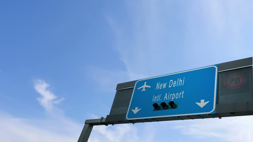 airplane flying over new delhi airport signboard
