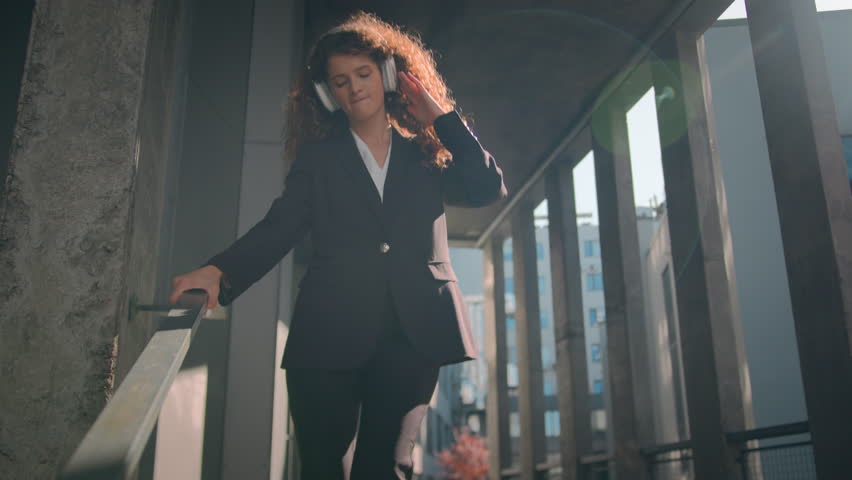 Happy girl Caucasian business woman funny carefree dancing outdoors free businesswoman walking down stairs of office building listening music in headphones freedom celebrate dance in city sun sunlight Royalty-Free Stock Footage #3435459169