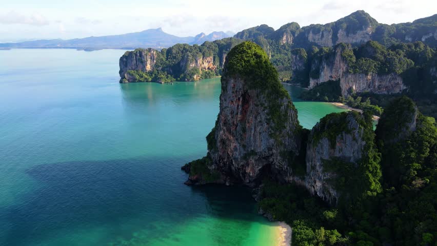 Railay Beach Krabi Thailand a tropical beach with a turqouse colored ocean, view from a drone of idyllic Railay Beach in Thailand in the evening at sunset with a cloudy sky Royalty-Free Stock Footage #3435480935