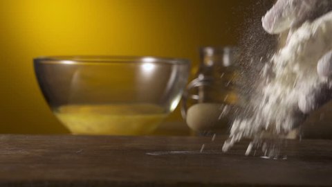 hand throwing flour on working surface
