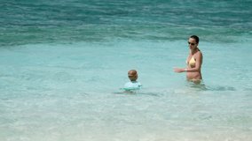 slow motion video of mother and child splashing in tropical water. 