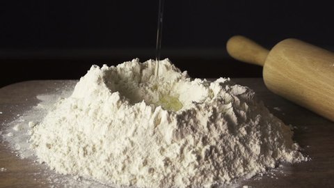 Child breaking an egg onto a heap of flour