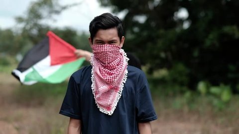 Close-up into the face of a male teenager wearing keffiyeh to cover his face