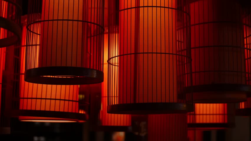 Lots of red paper lanterns in shape of cylinder put into metal cages hang on street and shine in the evening. Decorative lamps made in traditional Chinese style and often used for celebrating New Year Royalty-Free Stock Footage #3435530551