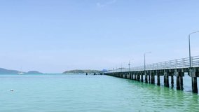 timelaspe 4k video at docking boats pier at tropical coean sea shore bank with calm sea ocean bay and sunshine cloudy background.tropical harbour landscape with blue sky and white cloud background