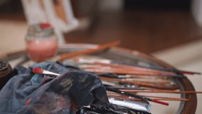 Artist puts color palette on round table in studio closeup. Man leaves wooden board with oil paint pigments in shop. Supplies for art manufacturing - Powered by Shutterstock - Get 15% off with code: PIKWIZARD15