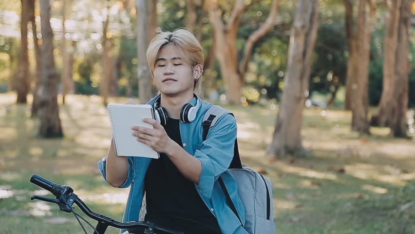 Portrait of a happy young man dressed in shirt with bag riding on a bicycle outdoors