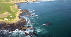 Drone video of waves hitting the rocks on the seashore next to a beautiful golf course