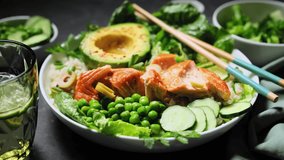 Salmon avocado bowl with broccoli, green peas, rice and fresh salad. Healthy food, poke bowl salad. Stock footage video 4k