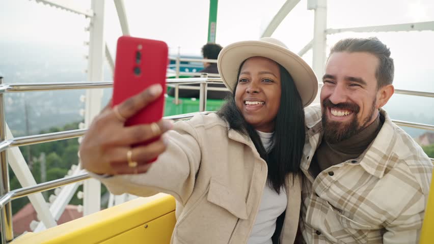 Romantic couple in love kissing and taking selfie portrait on cell phone on ferris wheel in amusement park  Royalty-Free Stock Footage #3435697489