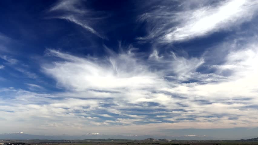 Time lapse of white cirrus clouds in a dark blue sky.