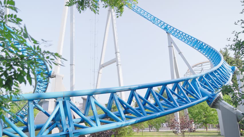 Roller coaster Ride against blue sky. Roller coaster in the amusement park. Cheerful entertainments in park of attractions