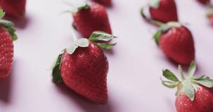 Animation of 100 percent organic text over strawberries on pink background. Fruit, healthy diet and vegan fresh food concept digitally generated video.