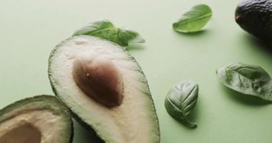 Animation of 100 percent organic text over halved avocado on green background. Fruit, healthy diet and vegan fresh food concept digitally generated video.