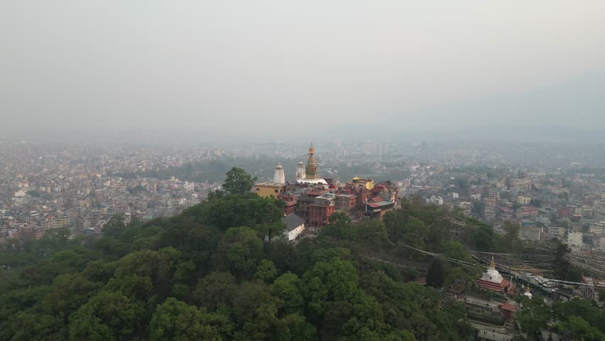 aerial drone shot zooming in on buddha temple on a hill In Kathmandu, Nepal at the base of the Himalayas
