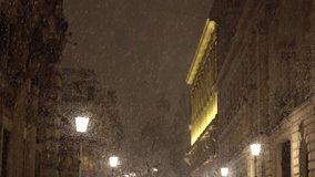 Winter in Bucharest. 4K video during a night snowfall on the streets of the city view to the old town, tilt camera movement. Travel to Romania.