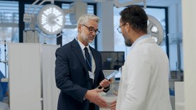 Pharmaceutical sales representative presenting new medication to doctor in medical building, shaking hands. - Powered by Shutterstock - Get 15% off with code: PIKWIZARD15